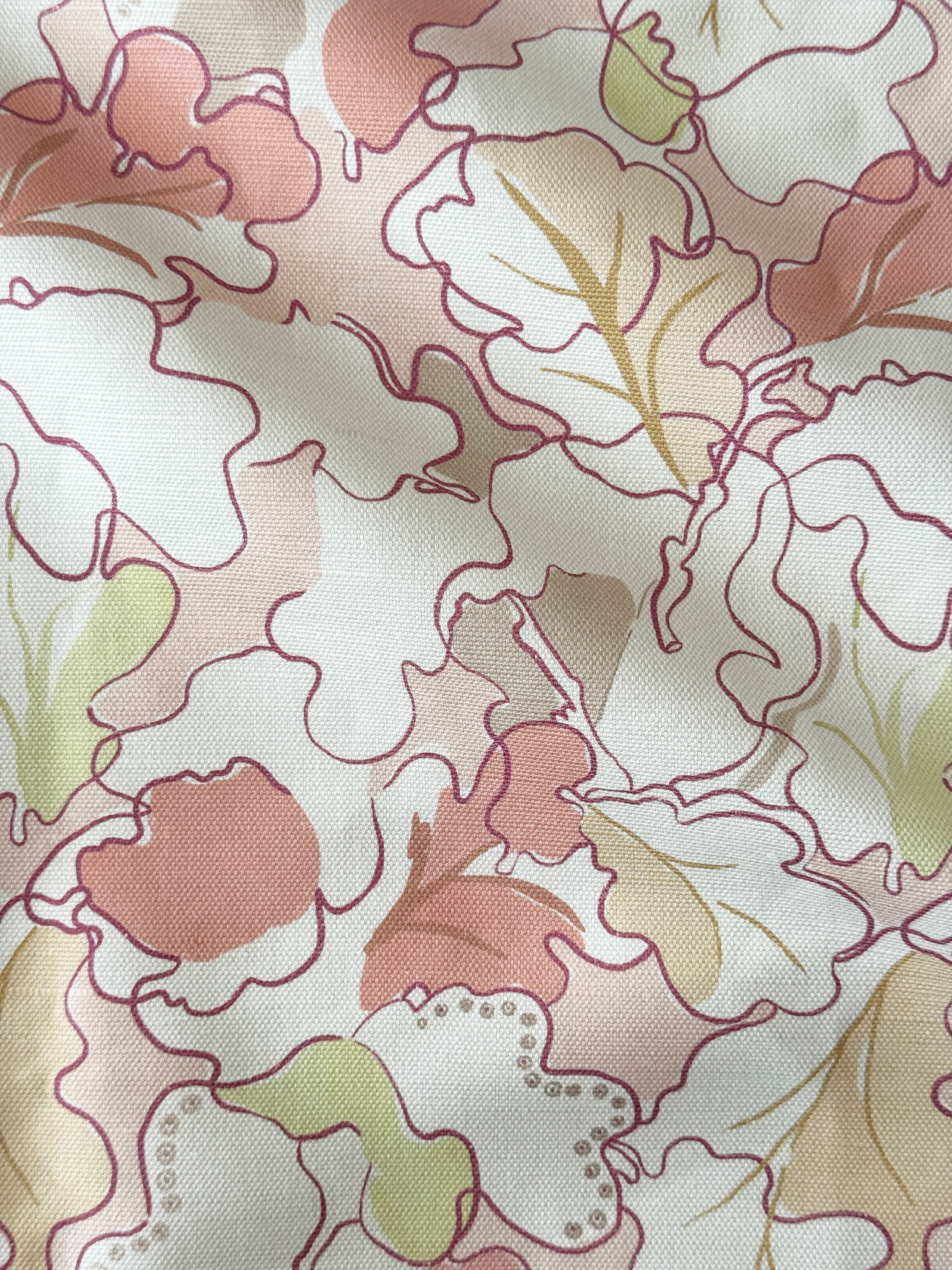 A close-up of a fabric pattern featuring large, abstract floral or leaf-like shapes outlined in dusty rose, with soft pink, sage green, and tan fills on an off-white background.