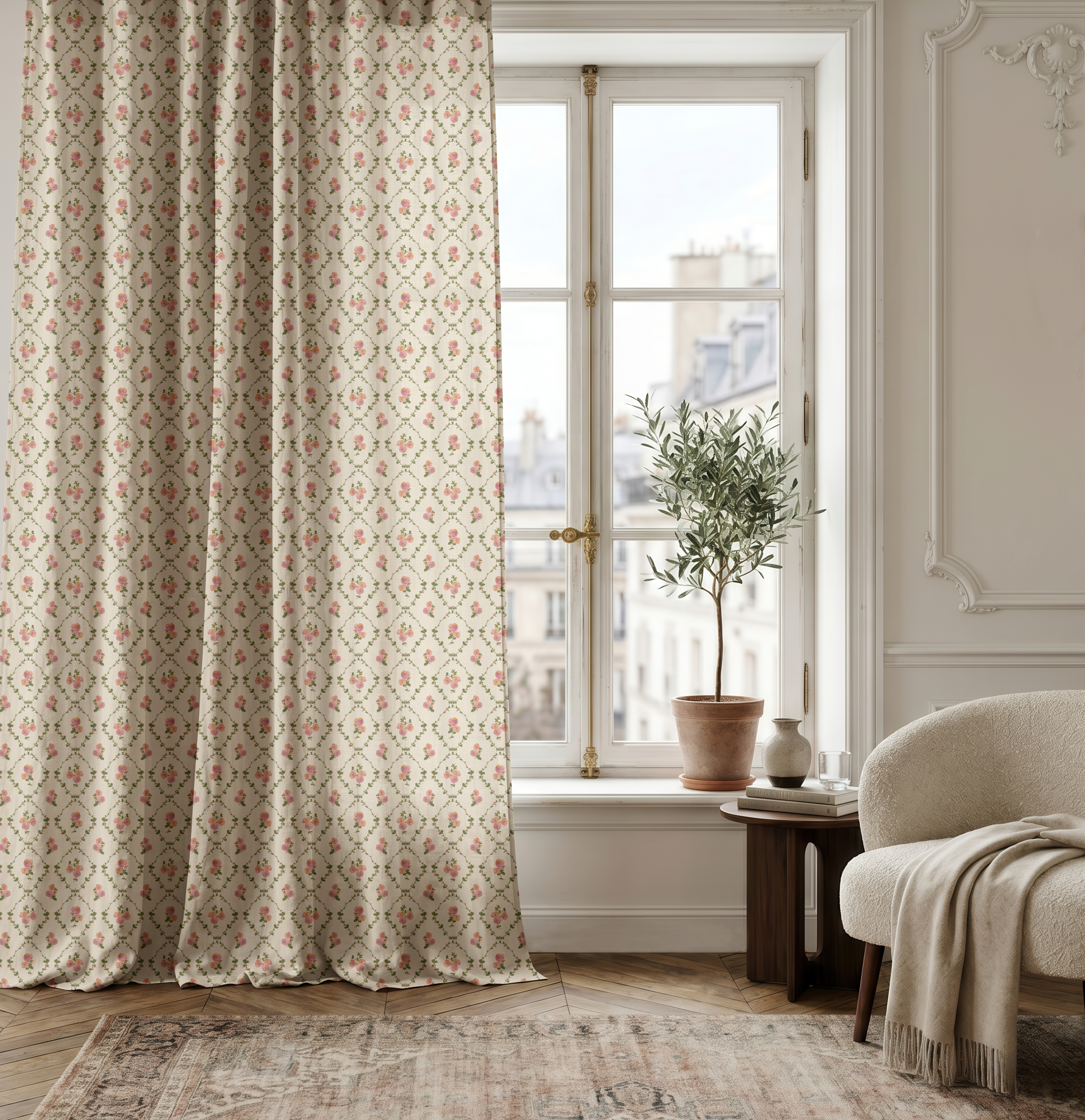 A pair of floor-length patterned curtains in a beige fabric with a small red and green floral motif, hanging on a window in a Parisian apartment with a potted olive tree, a cream armchair, and a light rug.