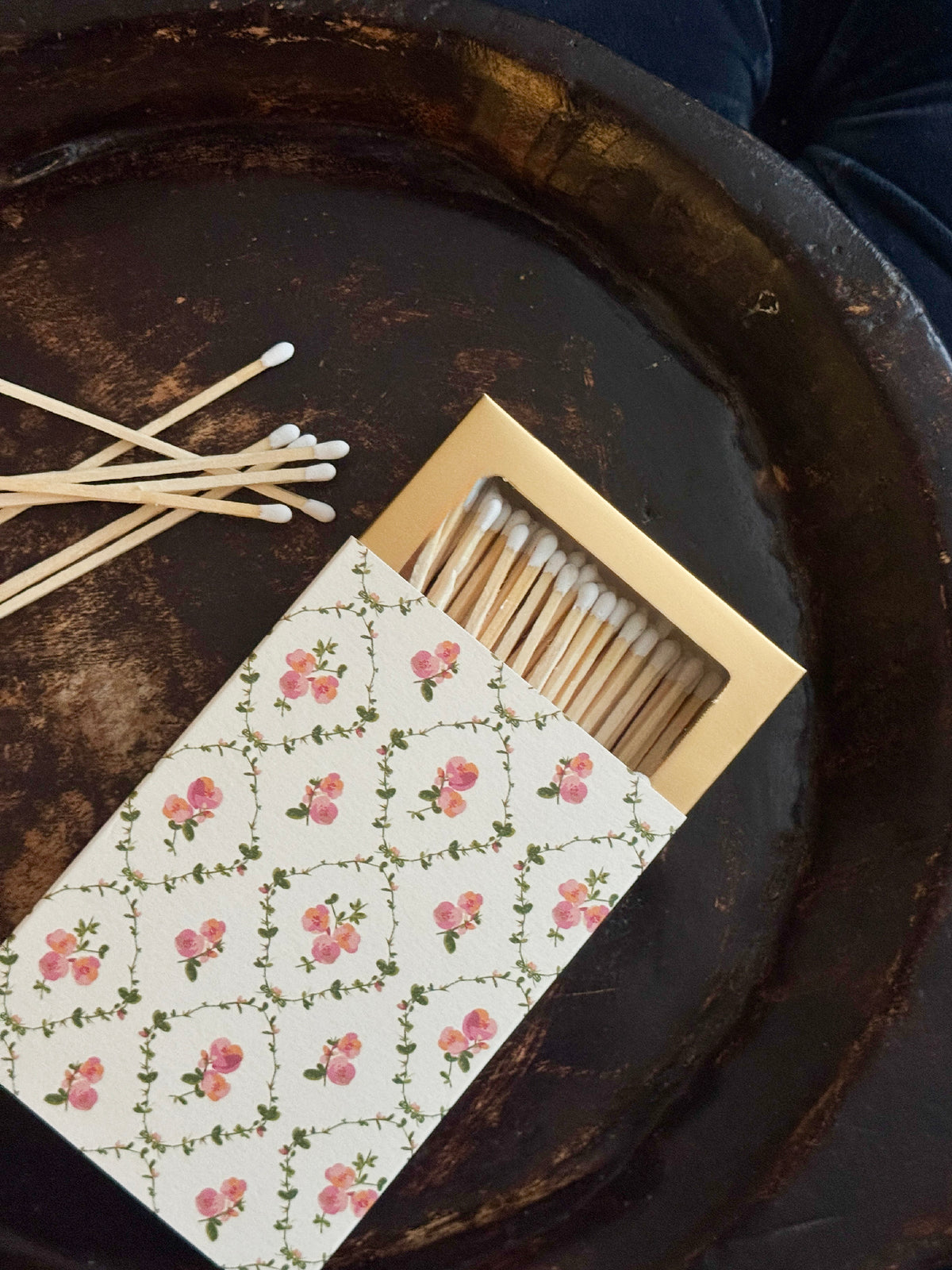 Decorative matchbox with flowers and long matches on a wooden tray